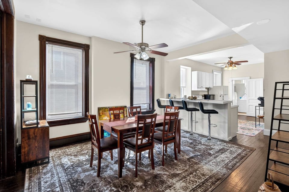 Gather, dine, and unwind in this light-filled open space featuring rich wood details, a cozy dining setup, and a sleek breakfast bar perfect for morning coffee.