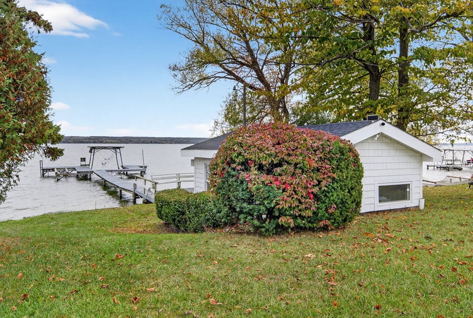 A peaceful stretch of shoreline framed by mature trees and open lawn—perfect for relaxing, exploring, or soaking in the calm lake atmosphere.