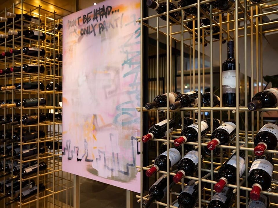 Admire curated bottles tucked into a dramatic, golden wine wall.
