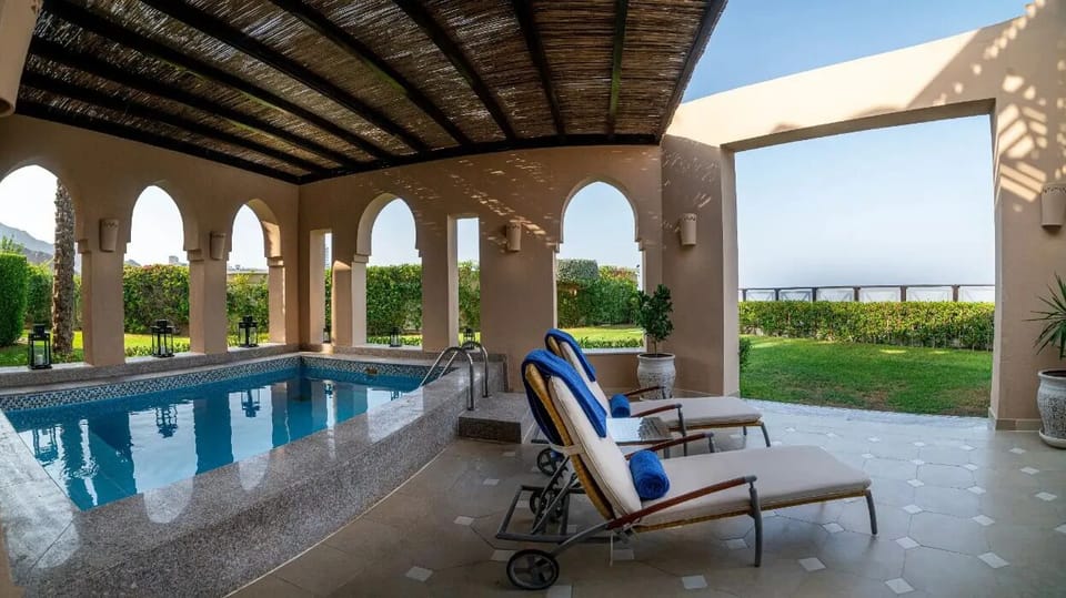 Unwind poolside under shaded arches with breezy sea air.
