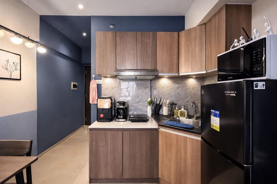 Fully equipped modern kitchen with fridge, microwave, coffee maker, and complete cooking essentials.