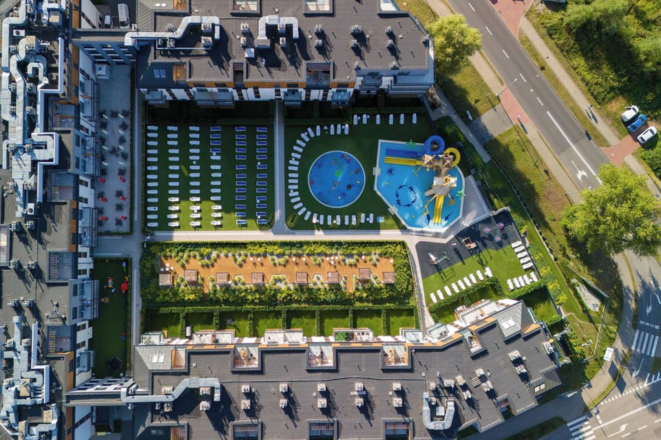 A top-down perspective reveals the layout of the buildings, showing the integrated swimming pool and sun loungers. The estate is meticulously planned with plenty of green spaces and recreational facilities.