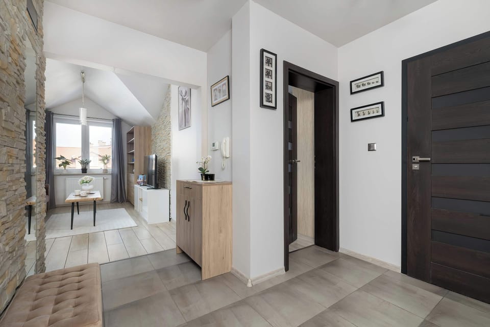 A bright hallway with light-colored tiles and wooden doors. The entryway feels clean and organized.