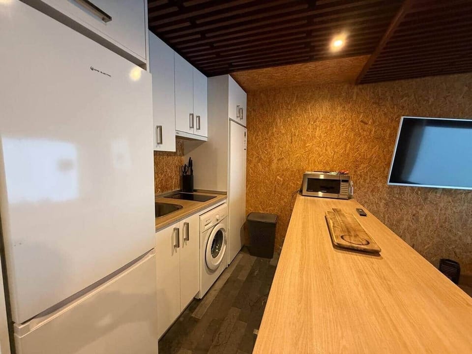 Cocina con lavadora, nevera y barra de madera