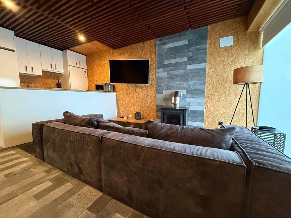 Salón cocina con TV, sofá y barra de desayuno