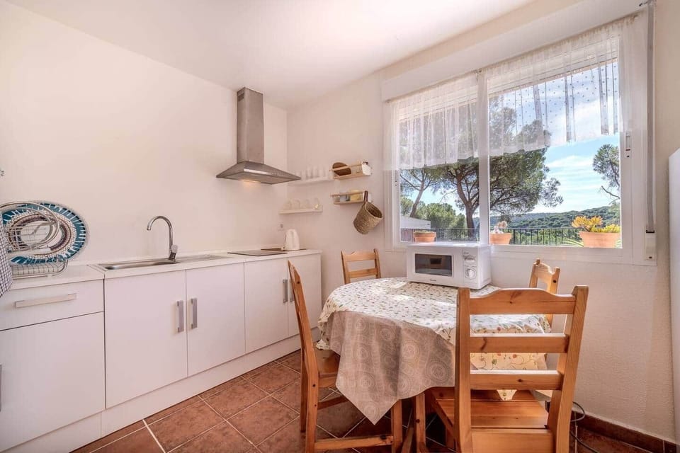 Cocina con campana, comedor y vistas al pinar