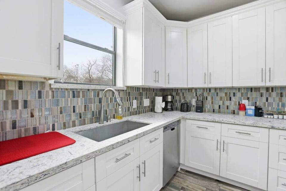 Natural light streams in at the sink through a wide kitchen window.
