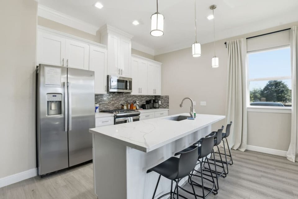 Stylish kitchen with quartz island, bar seating, and stainless appliances—bright, spacious, and perfect for meals or casual gatherings.