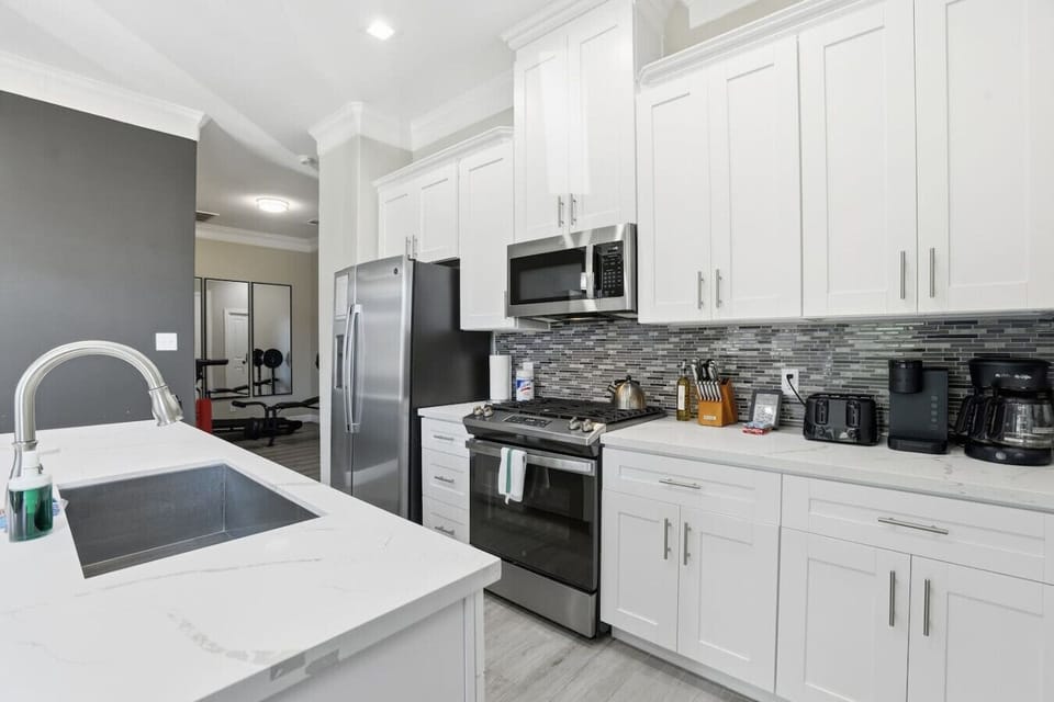Sleek cooking space featuring gas range, modern backsplash, generous storage, and prep-friendly island—designed for comfort and everyday use.
