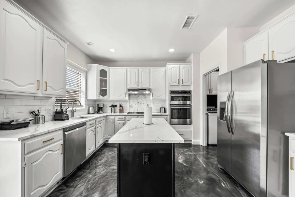 Fully equipped kitchen featuring modern appliances, ample counter space, and a large island—perfect for preparing meals with ease.
