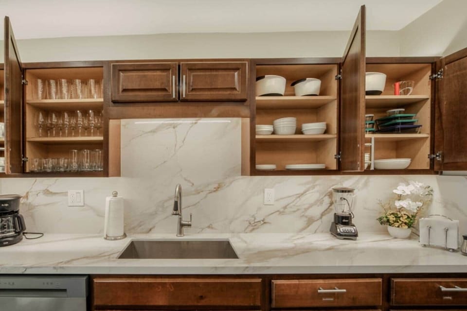 Kitchen is stocked with dishes, cups, glasses, wine glasses, bowls, pyrex storage containers, coffee mugs