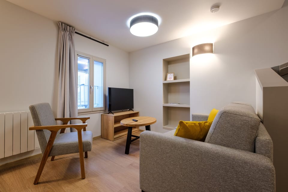 This bright living space includes a TV and stylish furnishings, offering a comfortable place to unwind together.