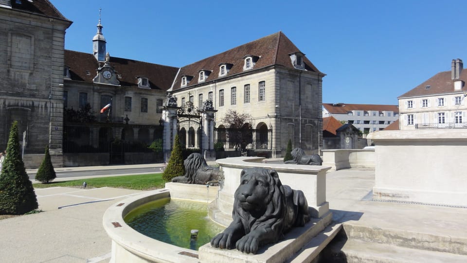 A striking fountain sculpture sits at the heart of the city centre, surrounded by historic buildings and open plazas.
