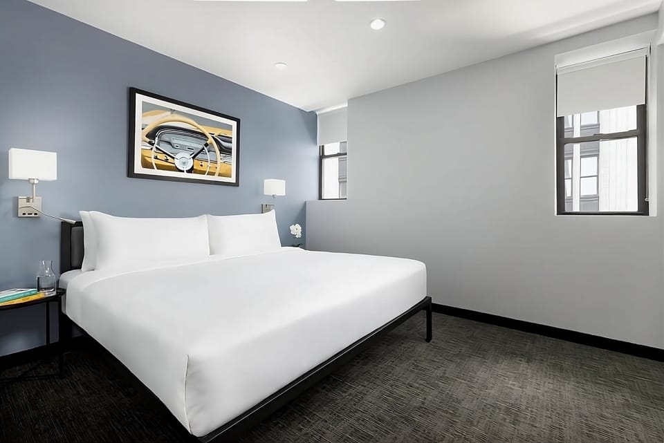 Unwind in crisp linens beneath warm, flattering bedside lighting.