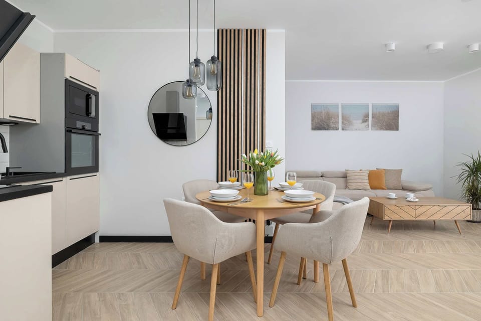 A wide shot of the modern kitchenette with white cabinetry and integrated appliances, connected to the dining space.