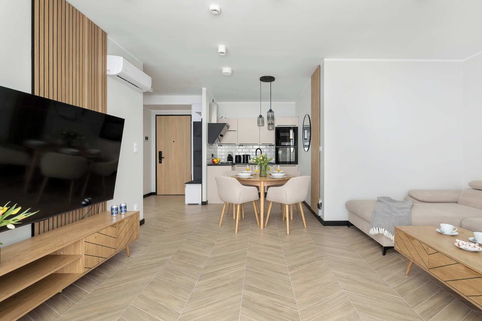 A view focusing on the wooden TV stand, large flat-screen television, and the flow into the dining area.
