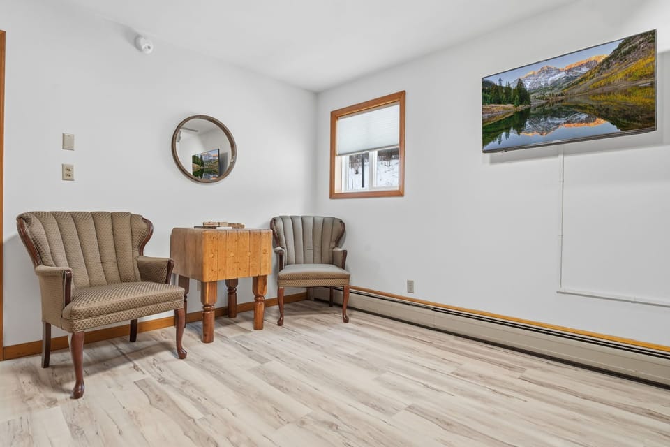 Cozy sitting nook  attached to the primary bedroom with comfortable chairs and wall-mounted TV—perfect for a quiet morning coffee or evening unwind.