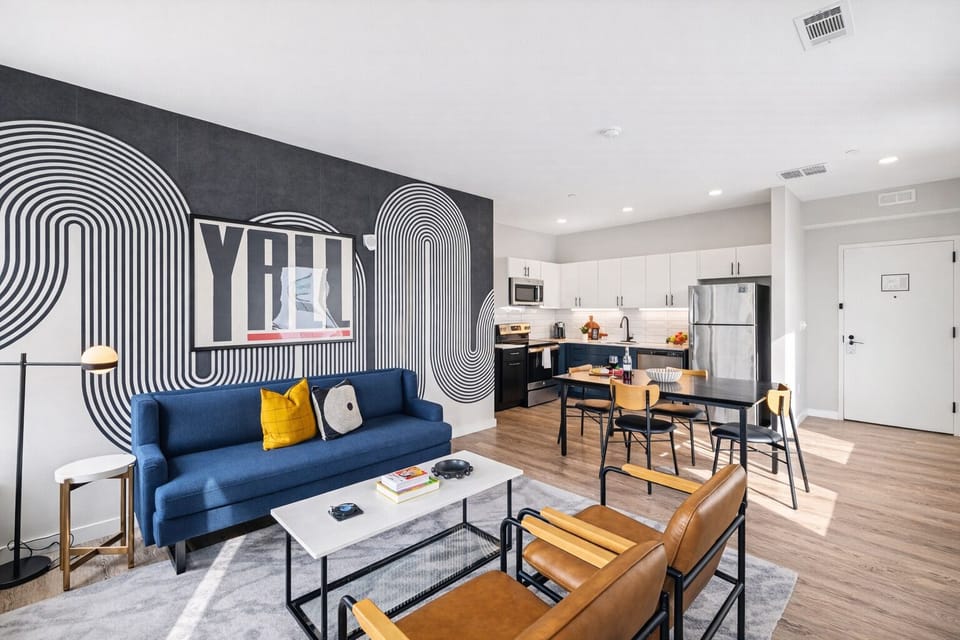 Unit 1: Bright open floor living space featuring a smart flat-screen TV and designer furnishings. Connects to the dining area and kitchen.