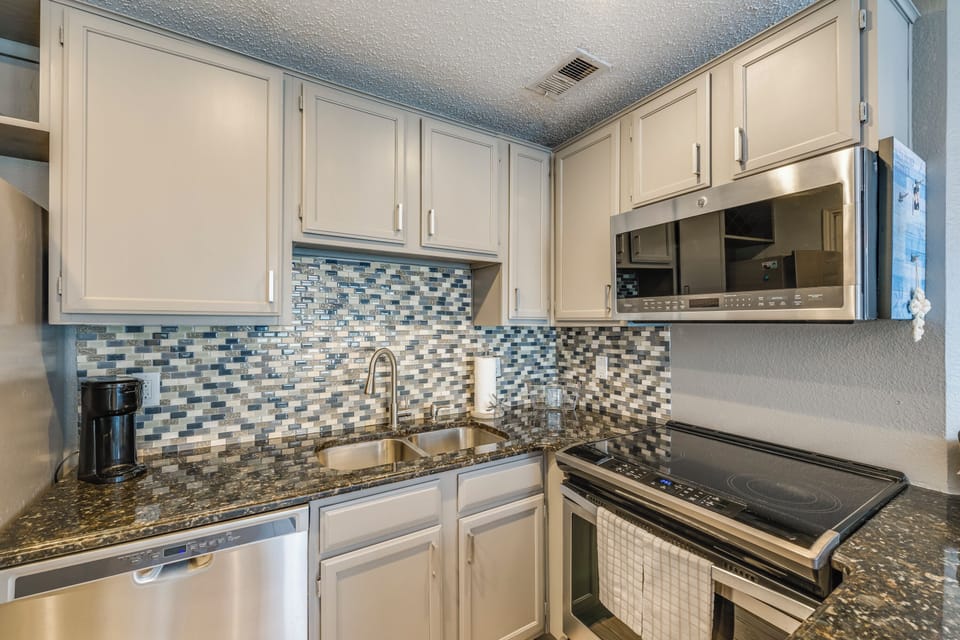 Your fully-equipped kitchen features granite counters, mosaic backsplash, stainless appliances, and everything needed for memorable home-cooked meals during your stay.