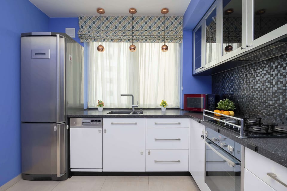 A small kitchen corner with white cabinetry and a patterned backsplash. The area is efficiently designed for everyday cooking.