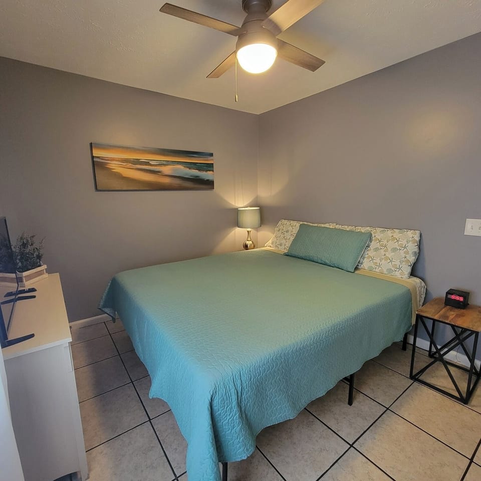 Bedroom with comfortable bed, ceiling fan with light, bedside lamp & nightstand