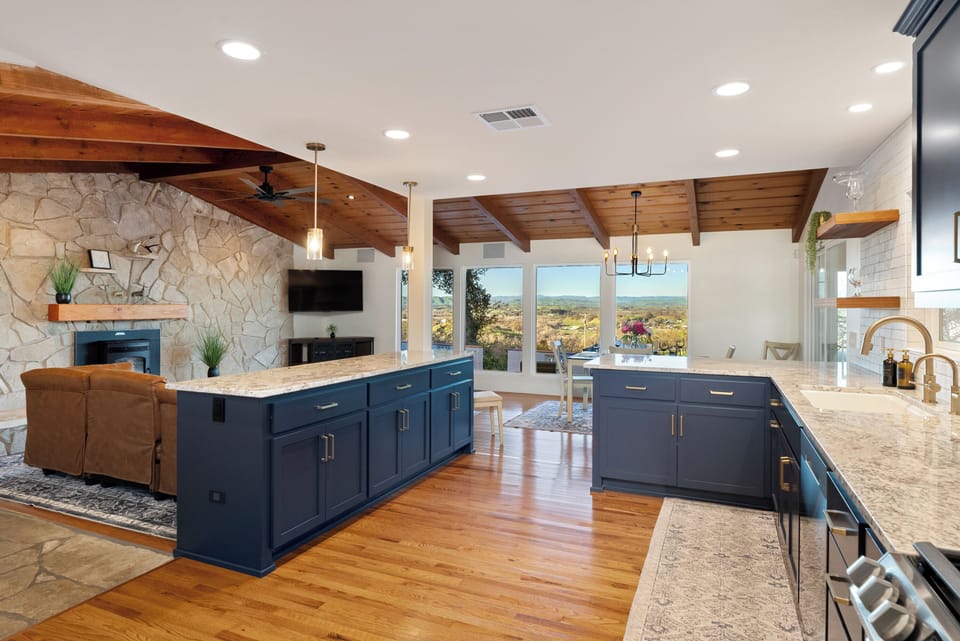 The kitchen's navy cabinetry is elevated by gold hardware and sleek built-in shelving, which offers a warm wood accent against the white subway tile backsplash. 