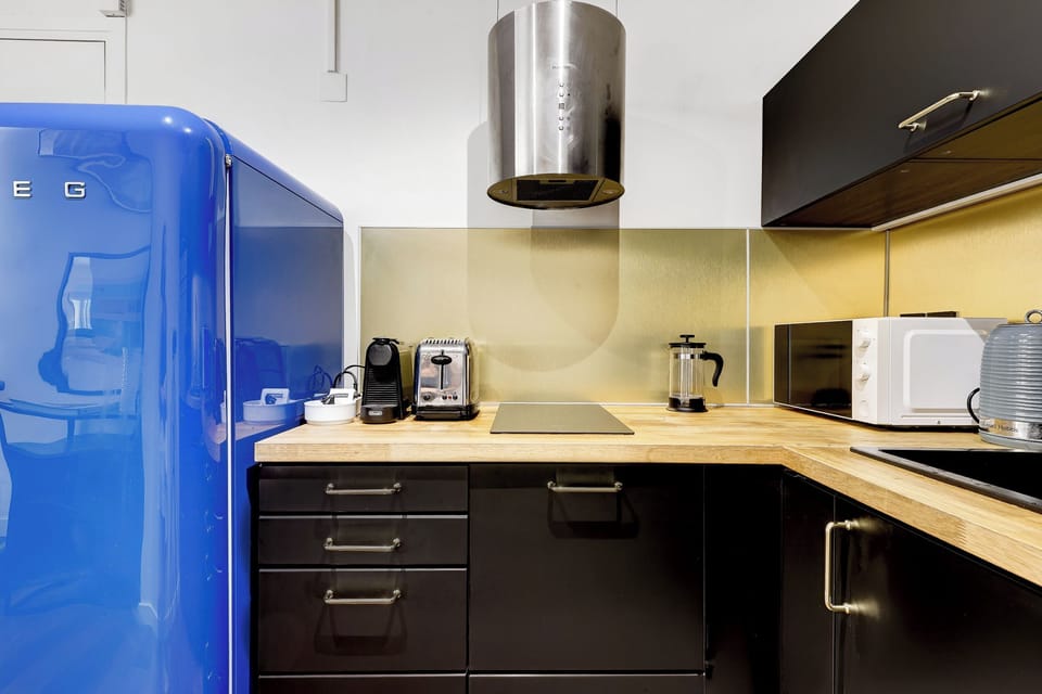 Cuisine design équipée, avec électroménager haut de gamme et frigo coloré.