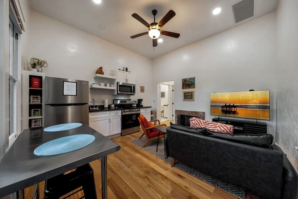 UNIT #1: Cozy, open concept space with kitchen, living room area with electric fireplace, and dining table for two