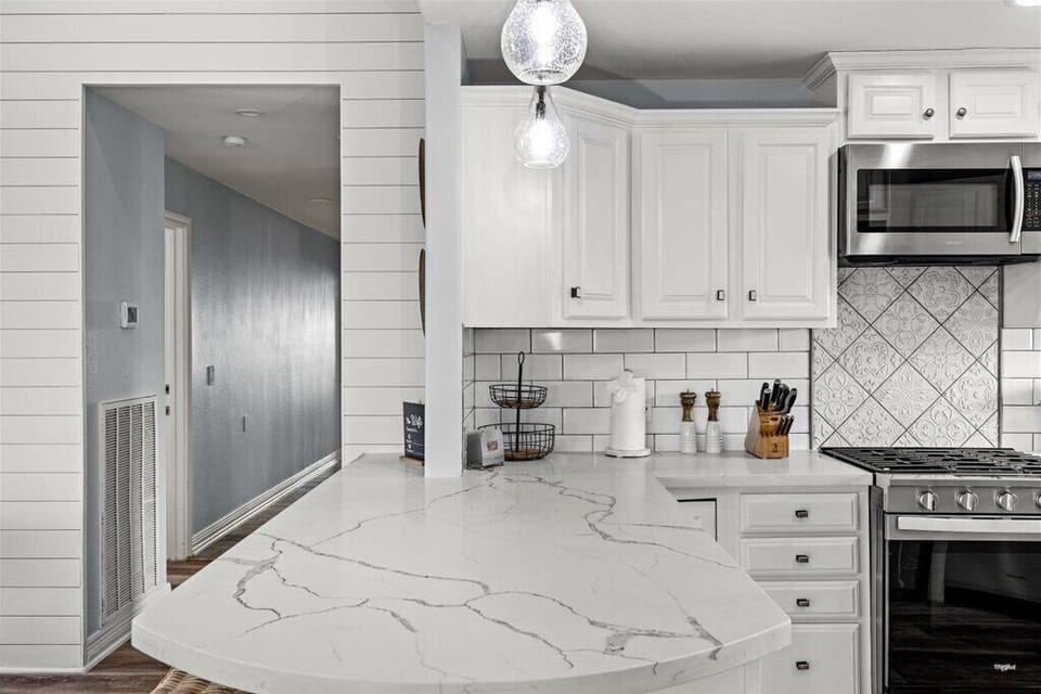 Bright farmhouse kitchen with quartz peninsula, subway tile, gas range