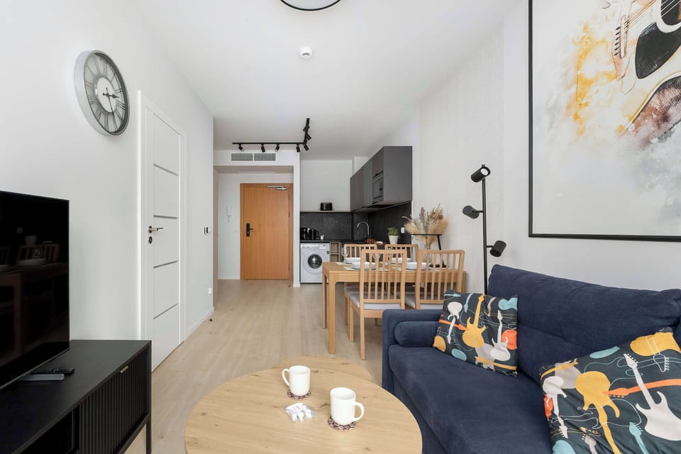 modern and thoughtfully designed living area connected to a fully equipped kitchen. Warm wooden accents, elegant furnishings, and natural light create a comfortable and inviting atmosphere for relaxing or dining together.