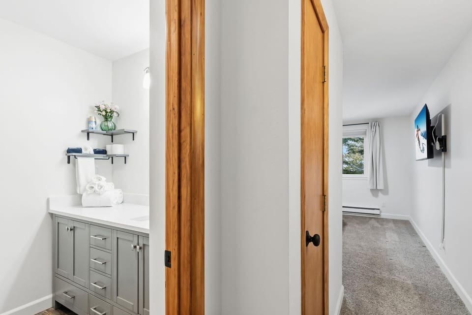 Step into your private bathroom featuring elegant grey cabinetry, crisp white countertops, and thoughtful storage for all your essentials.