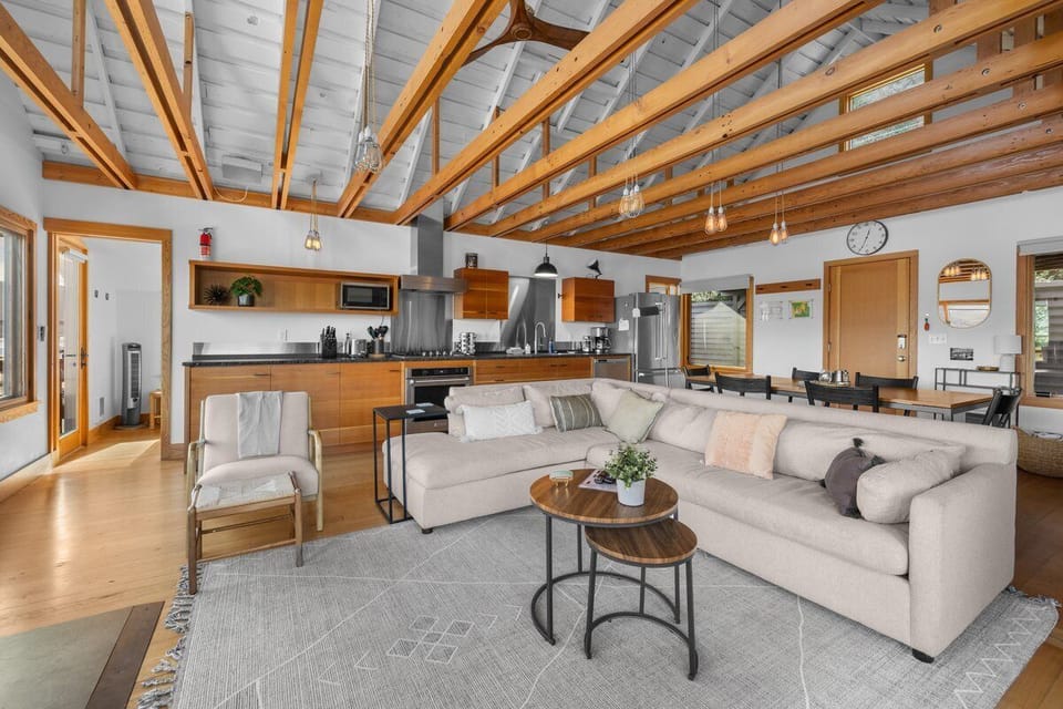 Unwind in your spacious open-plan living area, where exposed wood beams frame modern comfort and a fully equipped kitchen awaits.