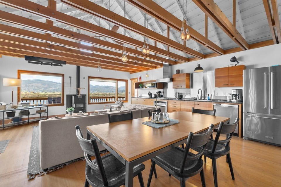 Gather around your spacious dining table beneath soaring wood beams while breathtaking mountain views frame every meal through floor-to-ceiling windows.