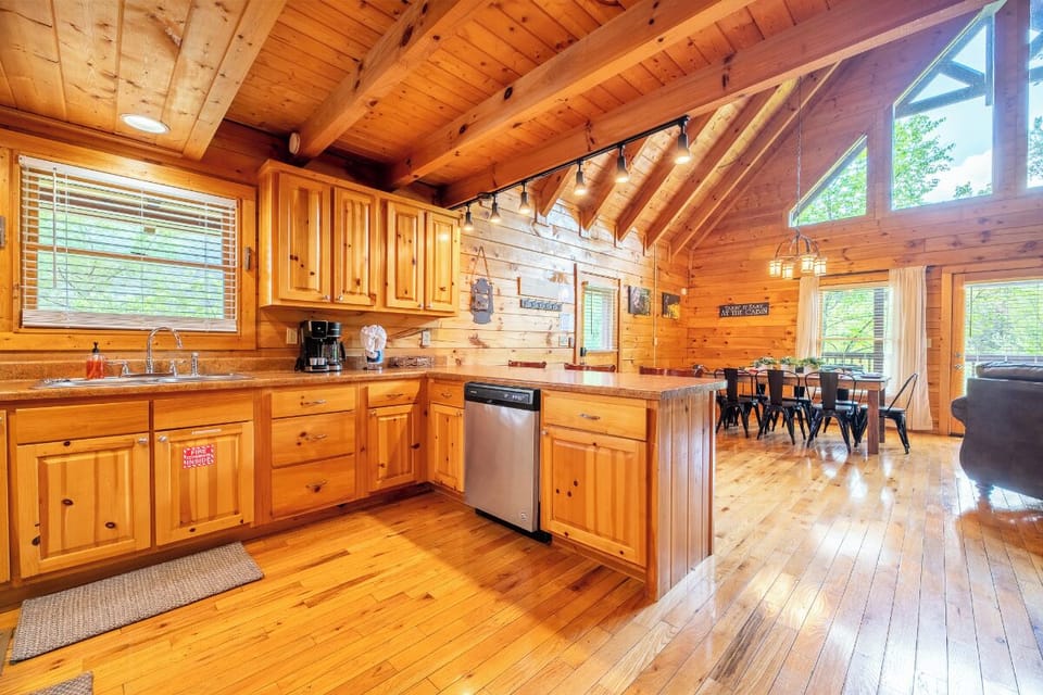 Your rustic kitchen invites culinary adventures with warm wood cabinets, modern appliances, and charming exposed beams overhead.