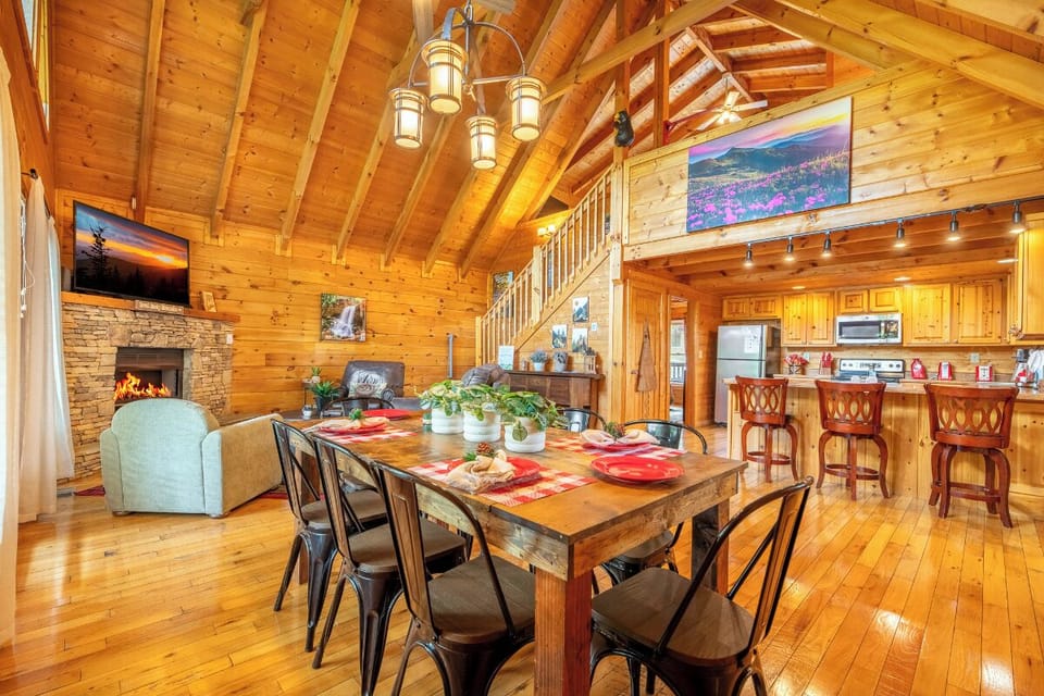 Gather around this rustic dining table where memorable meals unfold beneath soaring timber beams, with a crackling fireplace warming your evenings.