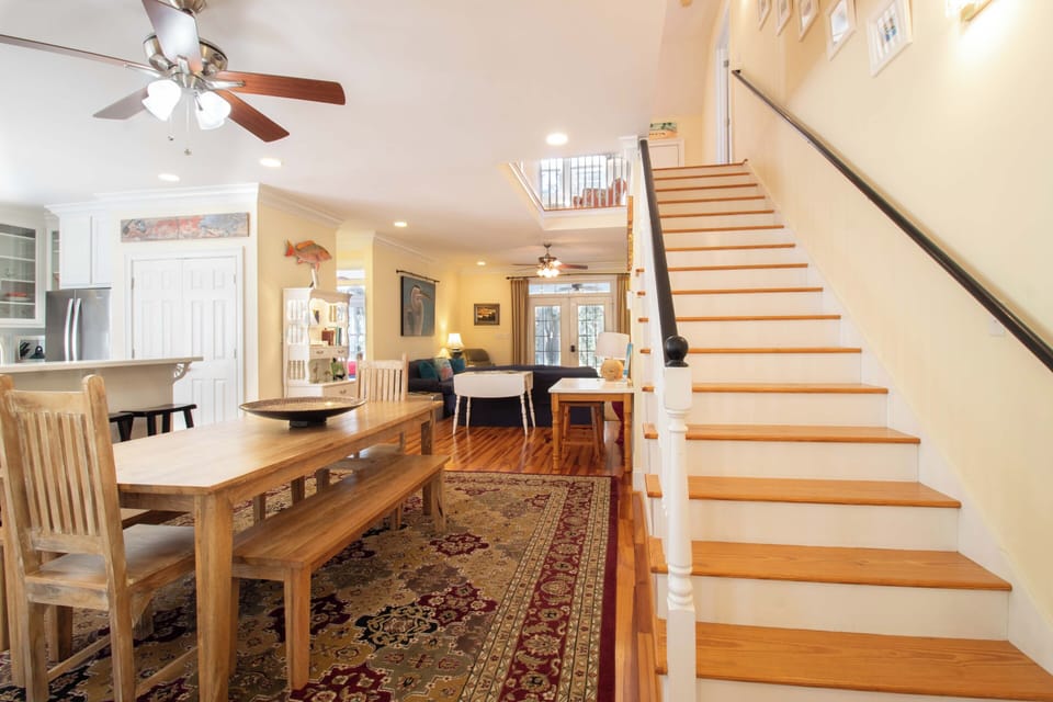 Discover your open-concept retreat where kitchen, dining, and living spaces flow seamlessly together, crowned by elegant wood stairs leading to your upstairs sanctuary.