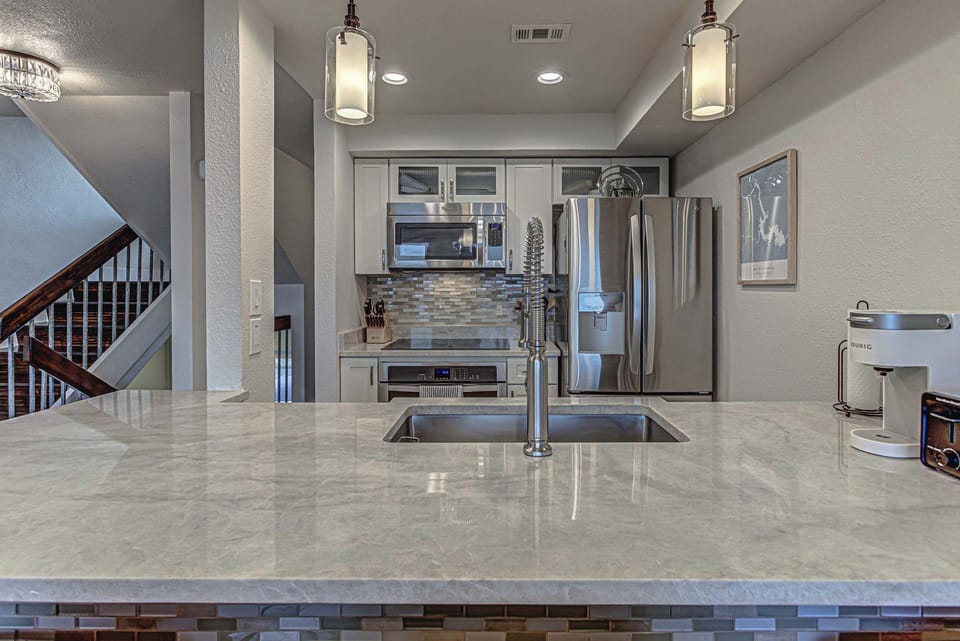 Modern kitchen with stainless appliances, breakfast bar seating, and open lake views.