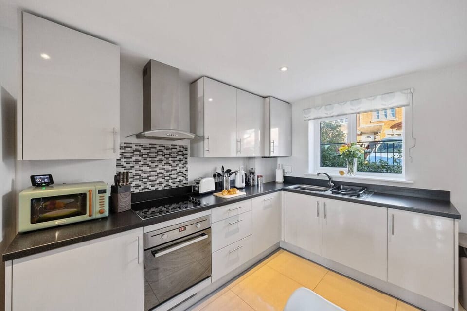 A modern fitted kitchen with an oven, hob, microwave and sink along the worktop