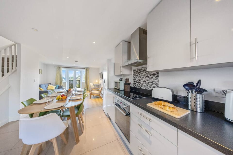 The open-plan kitchen and dining area with cabinets, worktop appliances and a dining table.