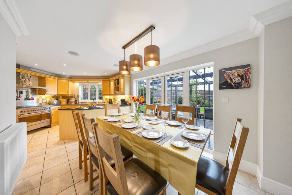 A long dining table laid with place settings next to an open kitchen area.