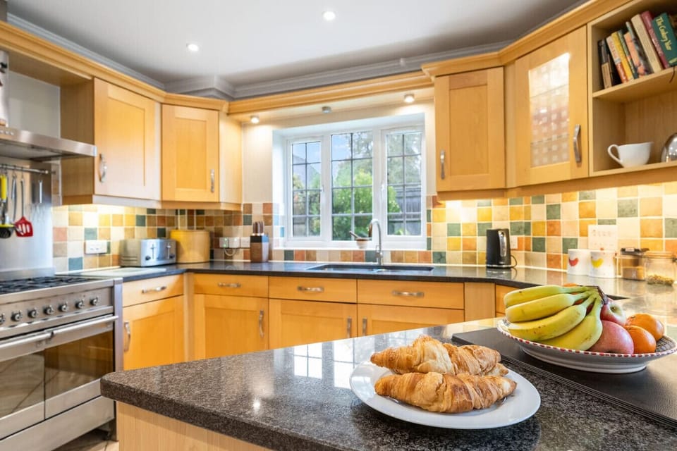 Kitchen worktop with fruit and pastries set out beside the hob and cabinets.