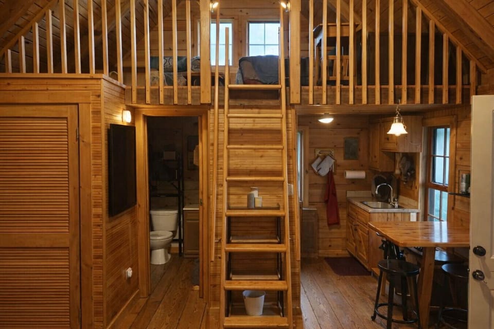 Cozy rustic cabin with loft bedroom, full kitchen, and private bath. Perfect for couples or solo travelers seeking a peaceful woodland retreat with warm wood interiors and charming cabin vibes.