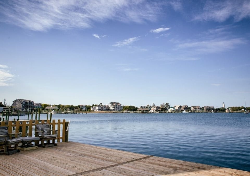 Waterfront deck with chairs and serene harbor views by the lighthouse