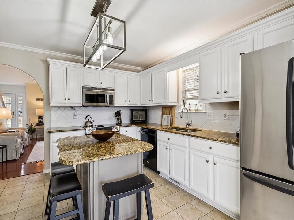 Cook family favorites in the open kitchen featuring a spacious island, stainless-steel appliances, and bright coastal finishes.
