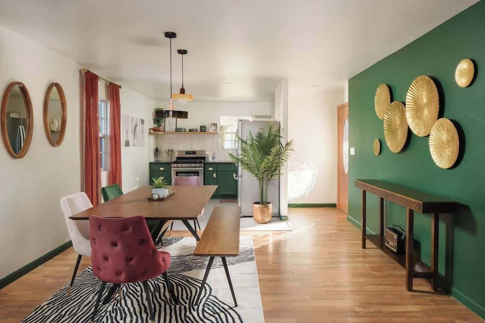 Dining nook with green accent wall, round table, and pendant lighting for intimate shared meals