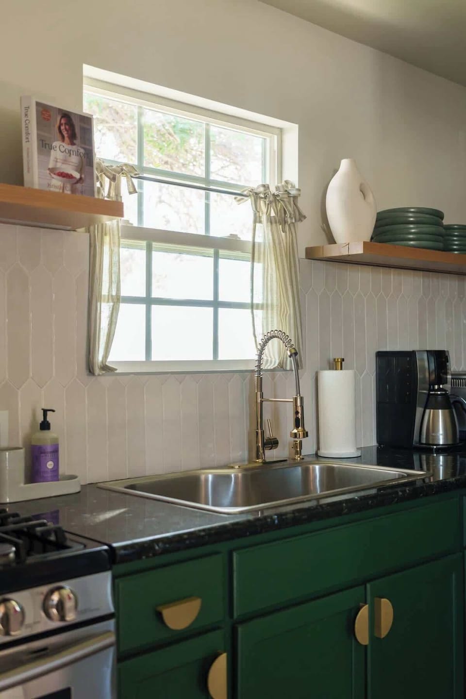 Compact kitchen alcove with green cabinetry, full-size appliances, and counter space for breakfasts 