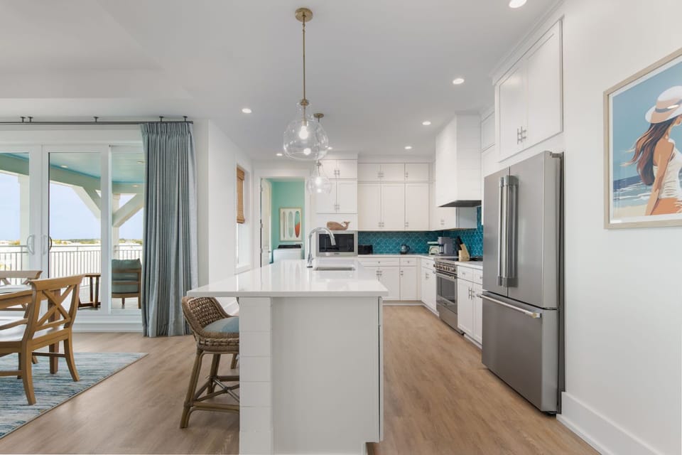 A spacious kitchen flows seamlessly into a dining area, offering a light and airy atmosphere with panoramic views of the Gulf beyond.