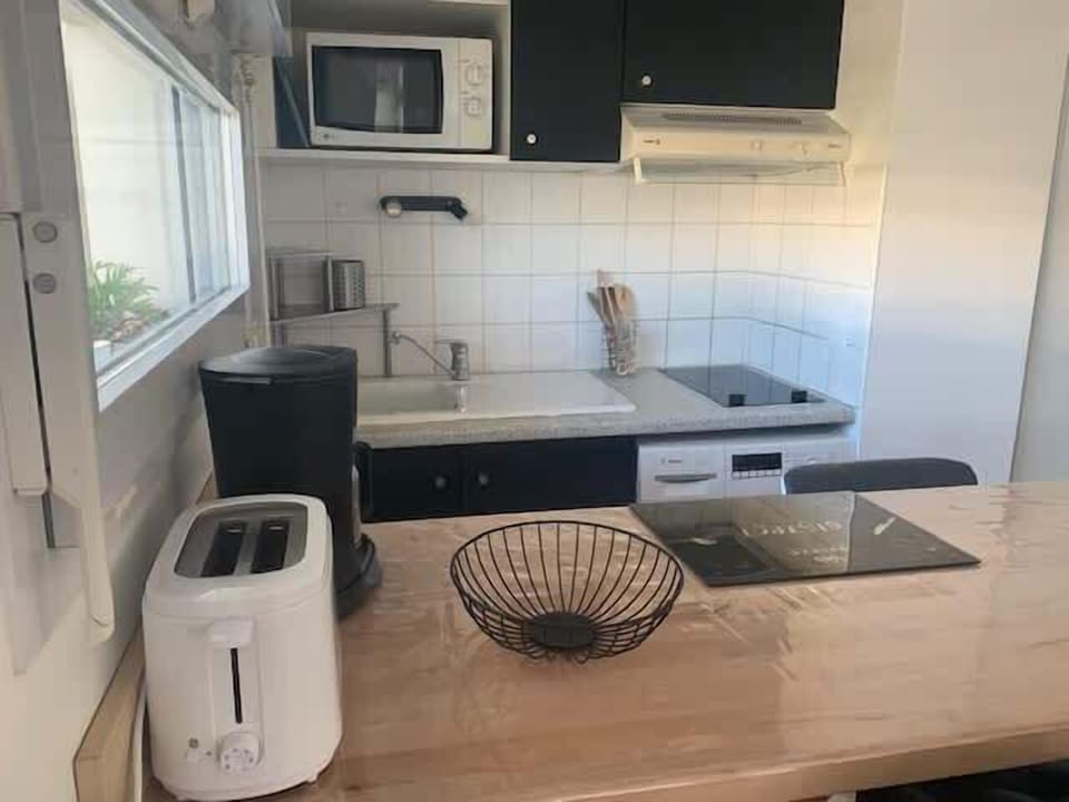 Cuisine composée d'un plan de travail en bois, four, micro-onde, grille-pain, plaques à induction ainsi qu'un lave vaisselle.