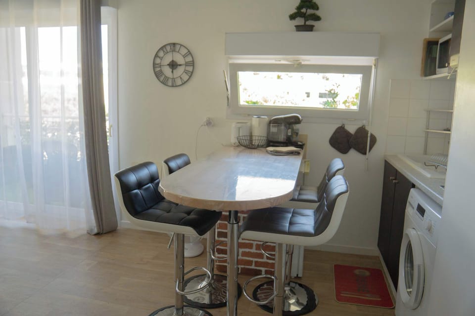 Salle à manger pour quatre personnes. Table haute avec tabourets noirs.