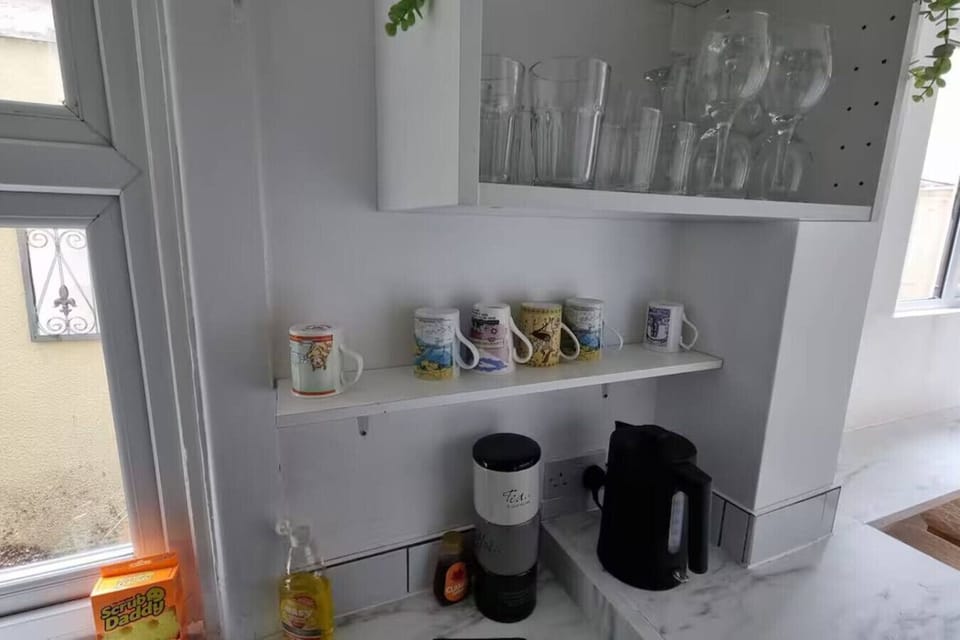 Kitchen counter laid out with mugs, a coffee maker, and items arranged on open shelving.